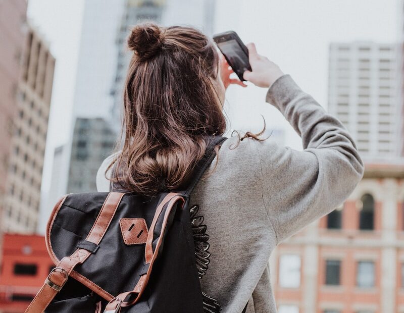 woman taking photo of high-rise building beside road